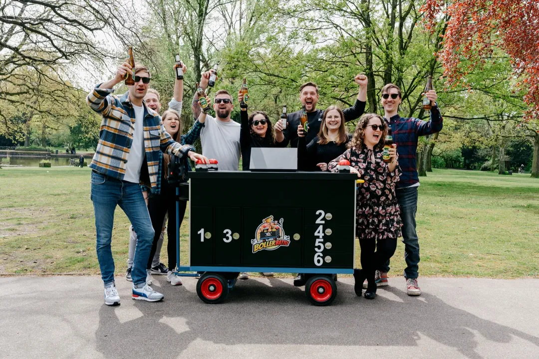 Eine große Gruppe jubelt und stößt hinter dem Battle-Wagen im Park an