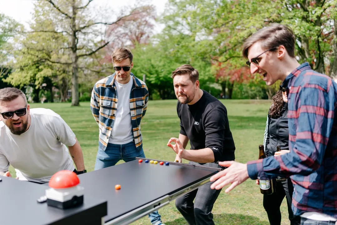 Eine Gruppe beugt sich lachend über das Curling-Spiel auf dem Battle-Wagen